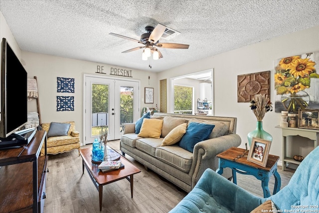 living room with light wood-type flooring, ceiling fan, a textured ceiling, and french doors