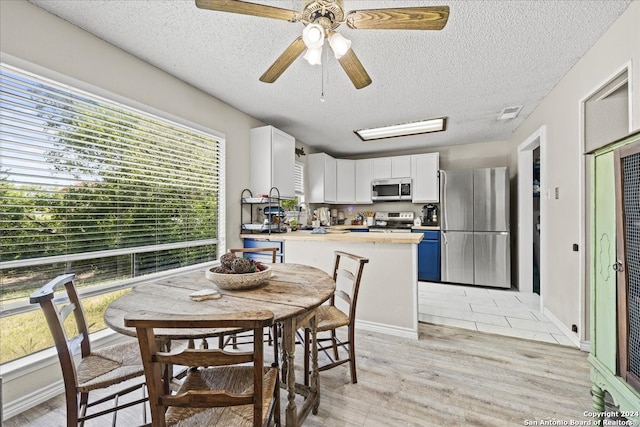 dining area featuring light wood-type flooring, a textured ceiling, a healthy amount of sunlight, and ceiling fan