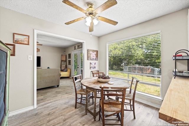 dining space with light wood-type flooring, ceiling fan, a textured ceiling, and a healthy amount of sunlight