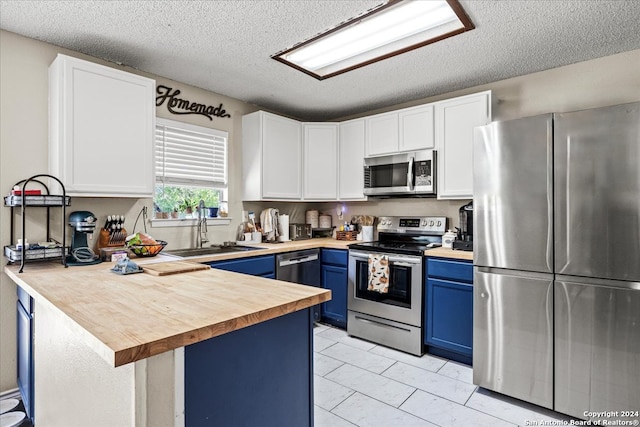 kitchen with blue cabinets, appliances with stainless steel finishes, sink, and white cabinets