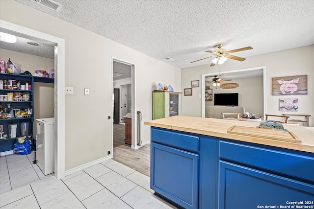 kitchen with light wood-type flooring, ceiling fan, blue cabinets, and a textured ceiling