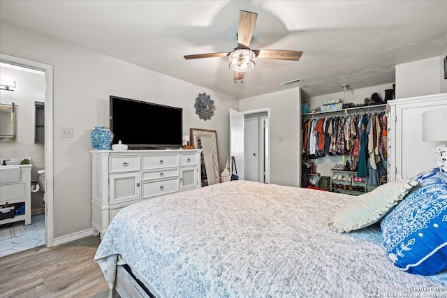 bedroom featuring light hardwood / wood-style flooring, ceiling fan, a closet, and ensuite bathroom