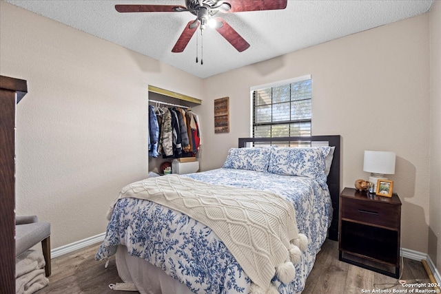 bedroom with a closet, ceiling fan, hardwood / wood-style floors, and a textured ceiling