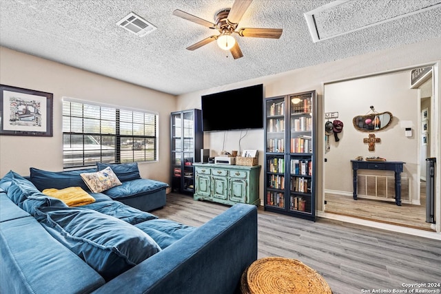 living room featuring a textured ceiling, ceiling fan, and light wood-type flooring