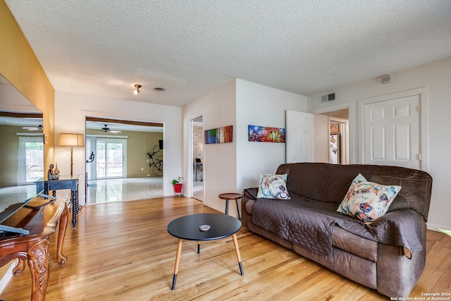 living room featuring a textured ceiling, ceiling fan, and light hardwood / wood-style floors