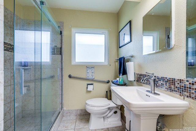 bathroom with toilet, plenty of natural light, decorative backsplash, and a shower with shower door