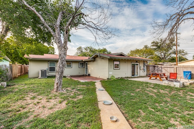 exterior space with central AC unit, a front yard, a patio area, and an outdoor fire pit