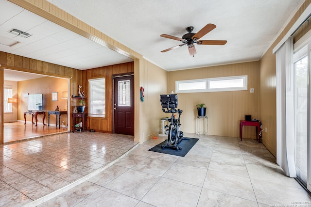 foyer entrance featuring a wealth of natural light, light tile patterned flooring, wood walls, and ceiling fan