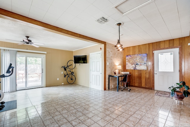 interior space featuring ceiling fan, wooden walls, beam ceiling, and light tile patterned flooring