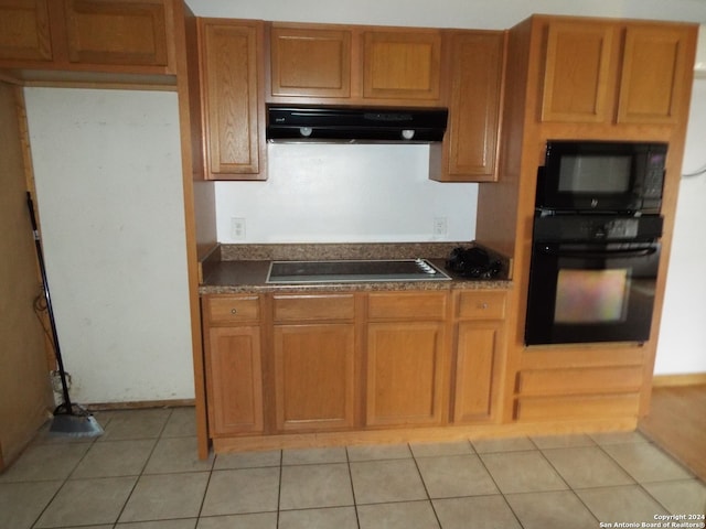 kitchen featuring black appliances, light tile patterned floors, and extractor fan