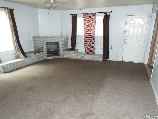 unfurnished living room featuring carpet, ceiling fan, and a brick fireplace