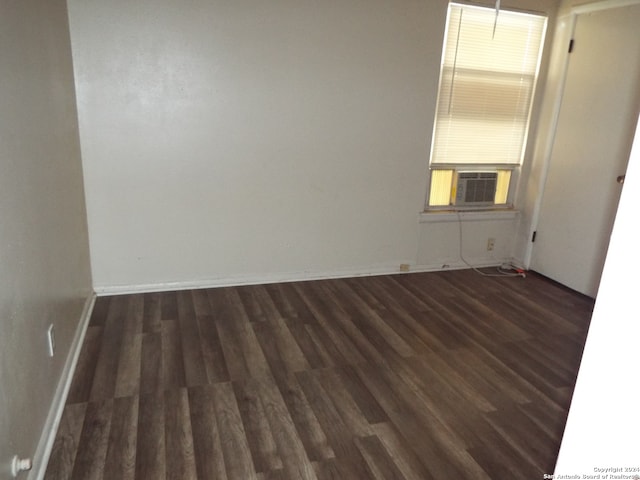 spare room with cooling unit and dark wood-type flooring