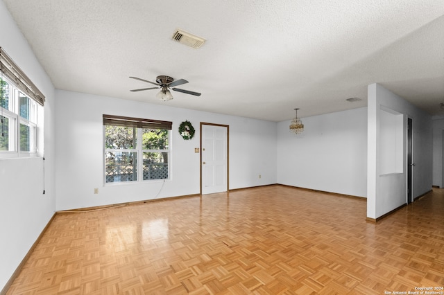 unfurnished room featuring light parquet floors, a healthy amount of sunlight, ceiling fan, and a textured ceiling