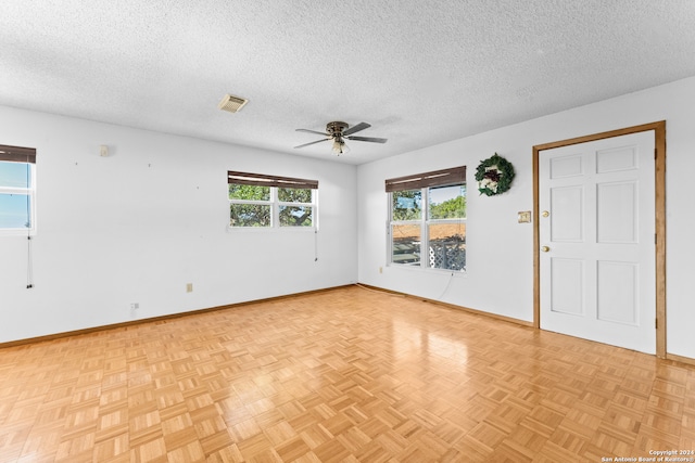 spare room featuring ceiling fan, light parquet floors, and a textured ceiling