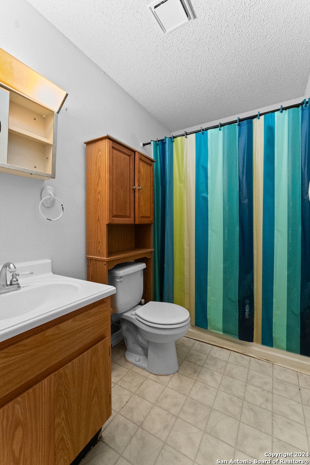 bathroom with curtained shower, toilet, a textured ceiling, and vanity