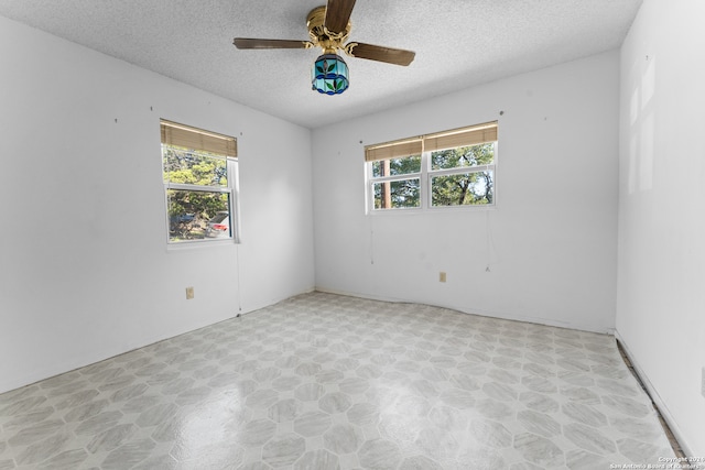 unfurnished room with ceiling fan, a wealth of natural light, and a textured ceiling