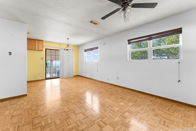 empty room featuring ceiling fan, light parquet floors, and a textured ceiling