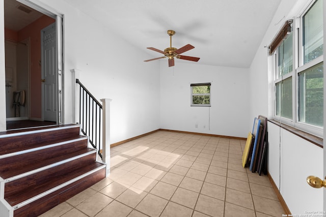 tiled empty room featuring vaulted ceiling, plenty of natural light, and ceiling fan