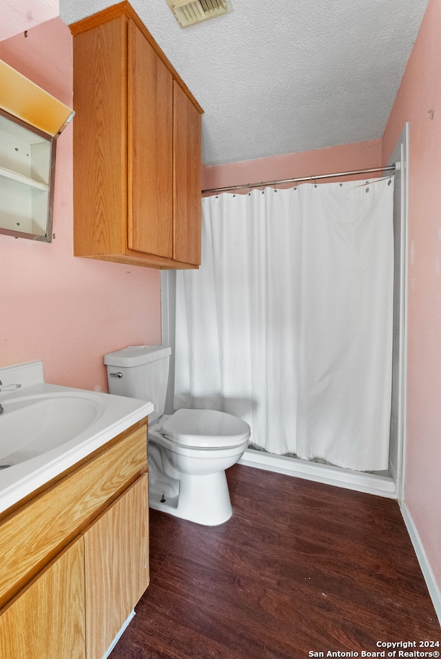 bathroom featuring toilet, vanity, a textured ceiling, wood-type flooring, and a shower with shower curtain