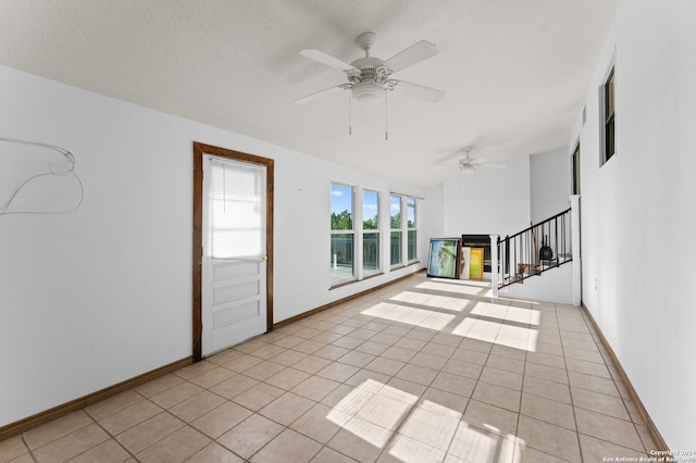 spare room featuring a textured ceiling, light tile patterned floors, and ceiling fan