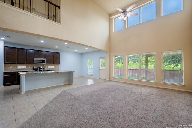 interior space with backsplash, sink, light tile patterned flooring, a high ceiling, and ceiling fan