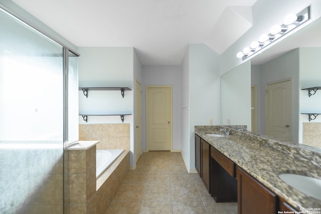 bathroom featuring tiled tub, vanity, and tile patterned flooring