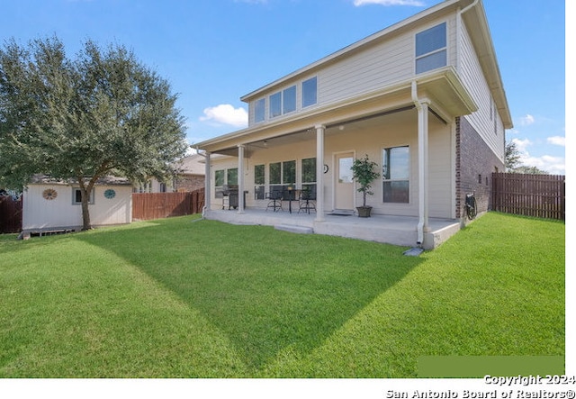 back of property with a yard, a patio, and a storage shed