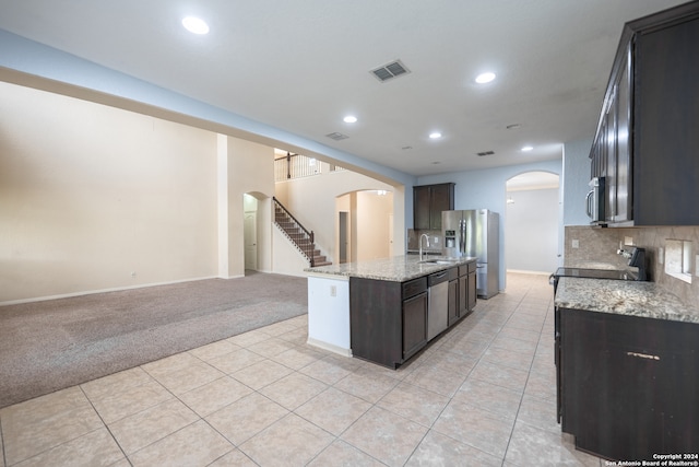 kitchen with light stone countertops, light colored carpet, stainless steel appliances, sink, and dark brown cabinetry