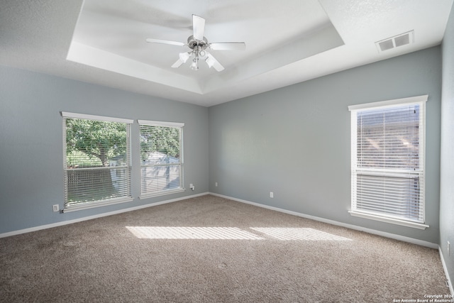 carpeted empty room with a tray ceiling and ceiling fan