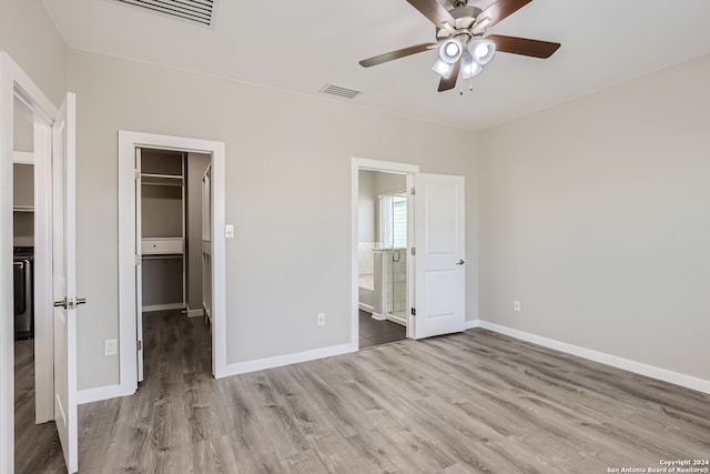 unfurnished bedroom with a closet, light hardwood / wood-style floors, a walk in closet, ensuite bathroom, and ceiling fan