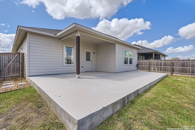 rear view of property featuring a lawn and a patio area