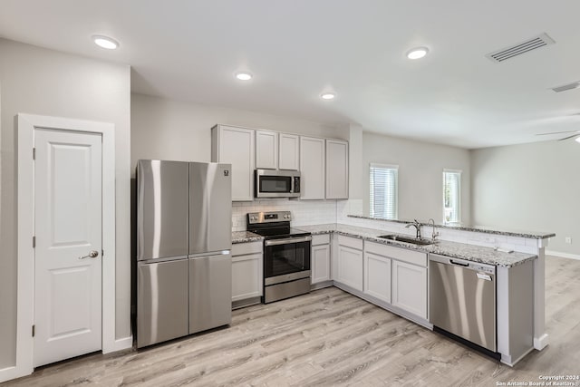 kitchen with light hardwood / wood-style floors, sink, stainless steel appliances, and kitchen peninsula