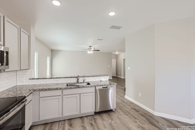 kitchen with light hardwood / wood-style floors, white cabinetry, stainless steel appliances, ceiling fan, and sink