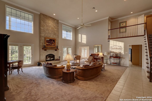 carpeted living room featuring a towering ceiling, ceiling fan, a fireplace, and ornamental molding