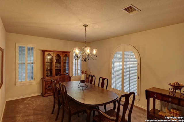 dining room with dark colored carpet, a textured ceiling, a notable chandelier, and a healthy amount of sunlight