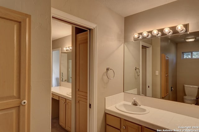 bathroom featuring a textured ceiling, vanity, and toilet