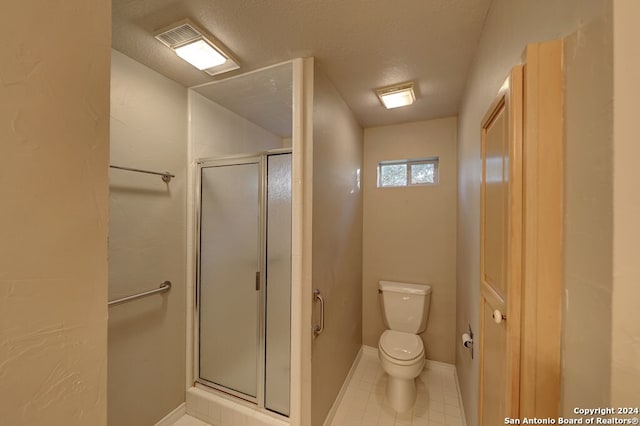 bathroom with a textured ceiling, toilet, tile patterned floors, and a shower with door