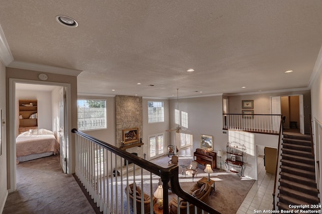 hallway featuring carpet floors, ornamental molding, and a textured ceiling