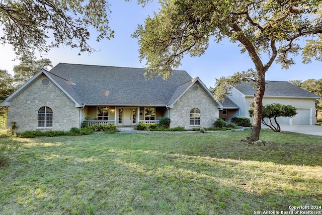 view of front of home featuring a garage, covered porch, and a front lawn