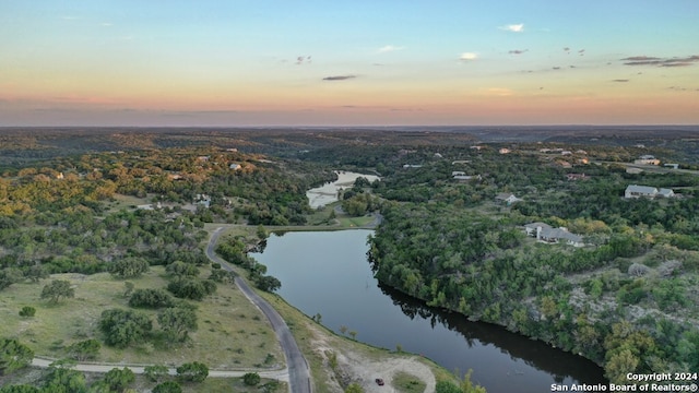 aerial view at dusk featuring a water view