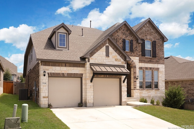 view of front of home featuring a garage, a front lawn, and central AC