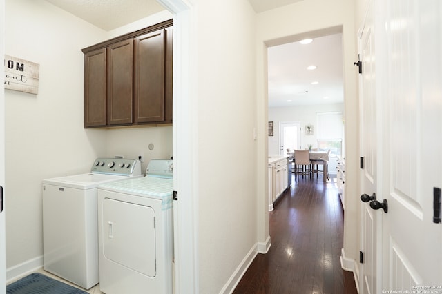 laundry room with washer and dryer, cabinets, and dark wood-type flooring