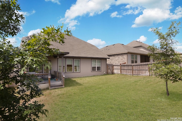 back of property with a lawn and a deck