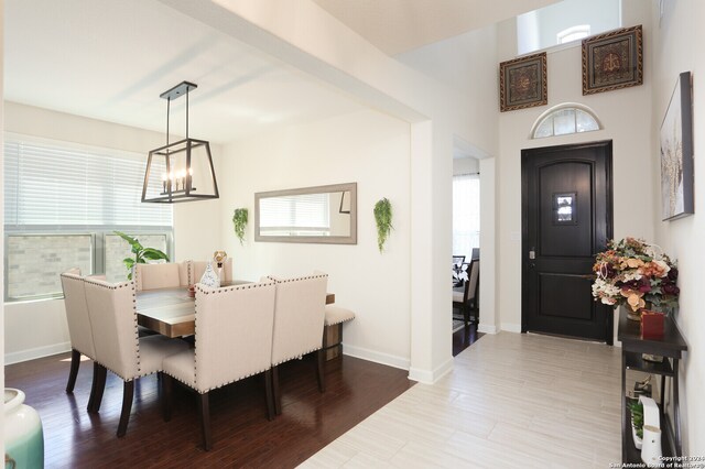 dining area with a wealth of natural light, an inviting chandelier, and wood-type flooring