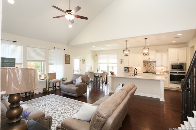 living room with a healthy amount of sunlight, ceiling fan, high vaulted ceiling, and dark hardwood / wood-style flooring