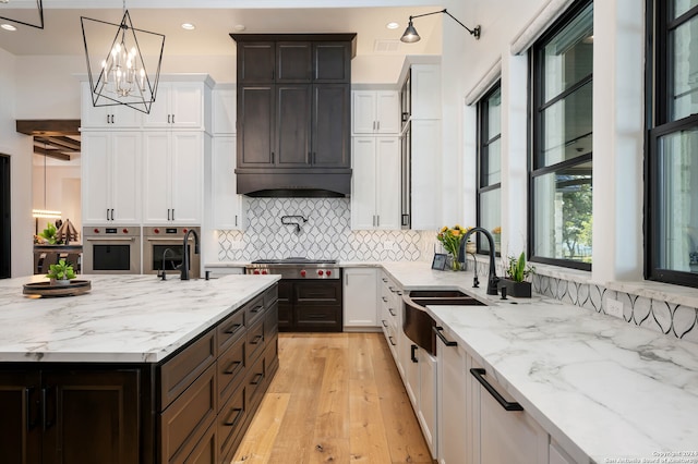 kitchen with an inviting chandelier, light hardwood / wood-style flooring, pendant lighting, appliances with stainless steel finishes, and sink