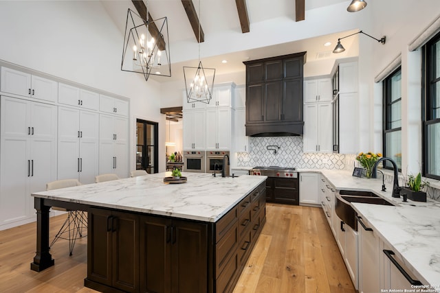 kitchen with dark brown cabinets, light hardwood / wood-style flooring, a center island, and decorative light fixtures