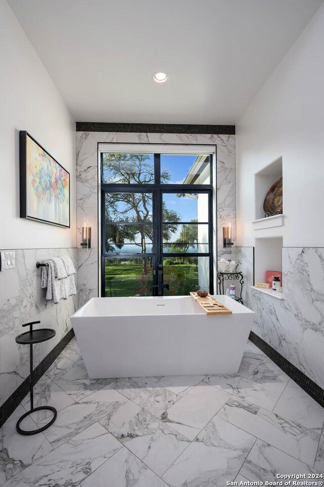 bathroom with tile walls, a healthy amount of sunlight, and a tub