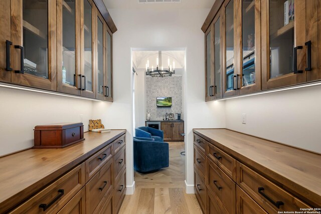 kitchen with butcher block countertops, light hardwood / wood-style floors, hanging light fixtures, and an inviting chandelier