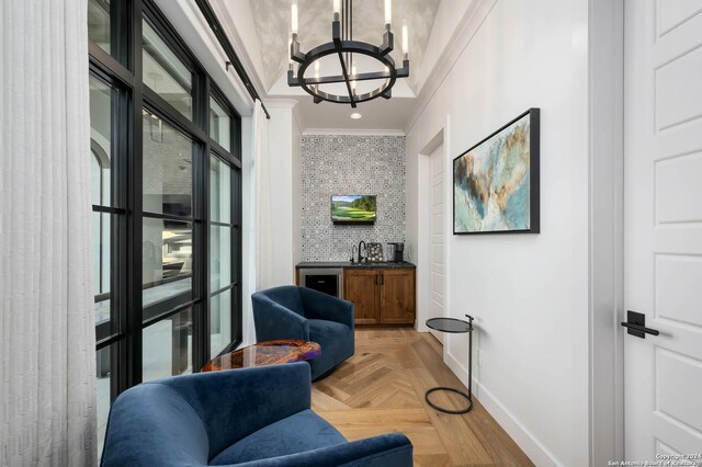 living area with light parquet floors, crown molding, a notable chandelier, and sink